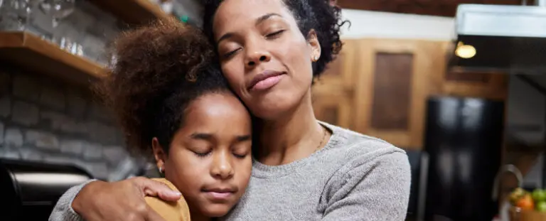 mother hugging her daughter with her their eyes closed in a kitchen domestic violence